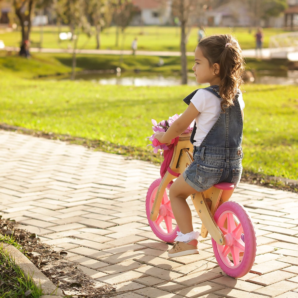 Menina em Biciquetinha rosa no parque