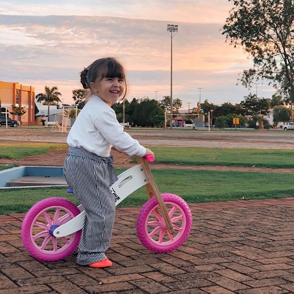 Menina sorrindo com Biciquetinha branca e rosa
