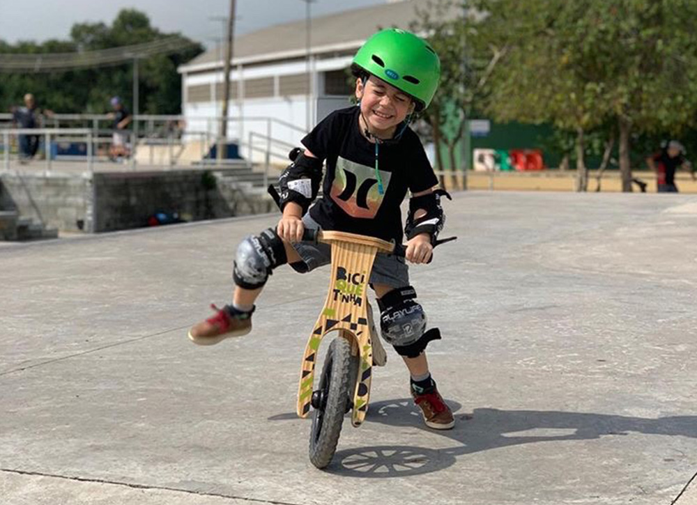 Noah andando de Biciquetinha com capacete verde